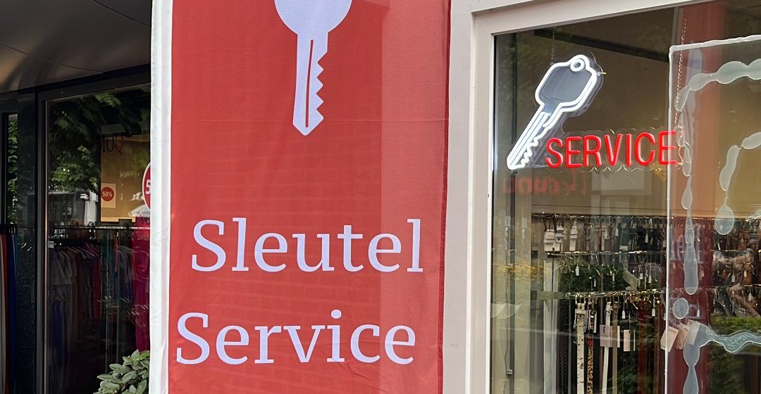 De rode Sleutelservice-vlag bij de ingang van Schoenmakerij Zeist aan de Slotlaan